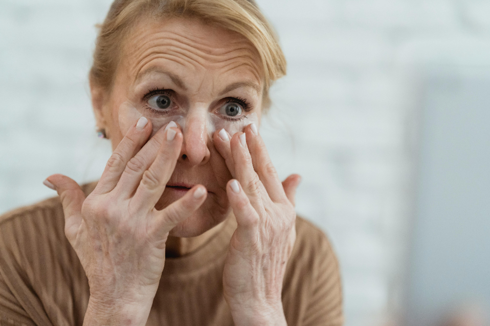 old woman applying product for wrinkles on her face 